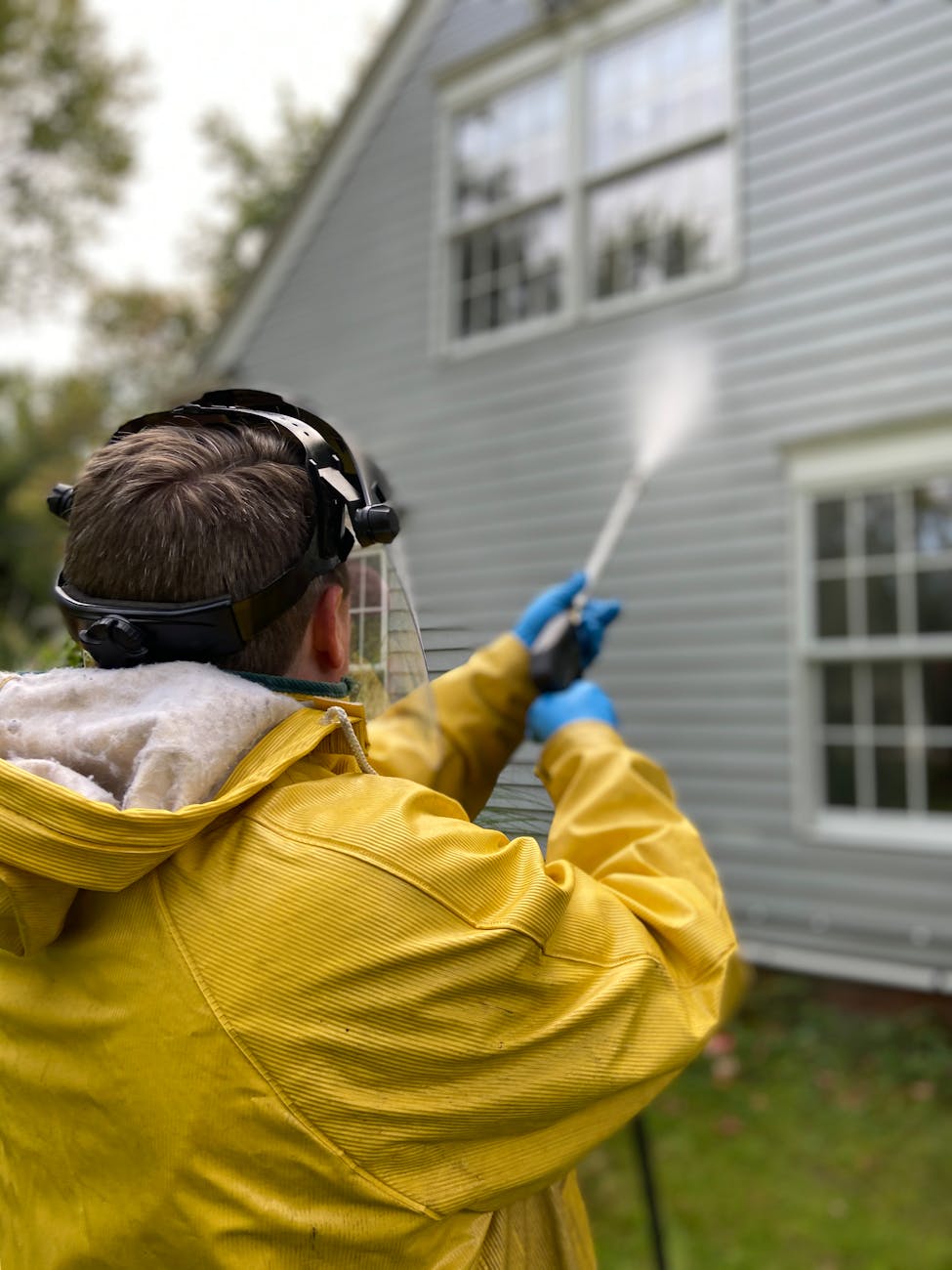 back view of a person pressure washing a house